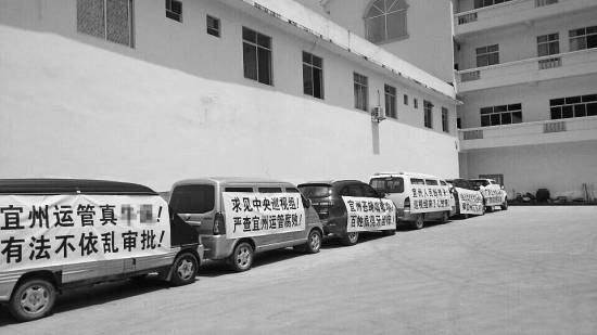 今年7月，宜州市運(yùn)管局通過(guò)了當(dāng)?shù)亓硪患臆嚈z企業(yè)開展?fàn)I運(yùn)車輛綜檢業(yè)務(wù)的備案，引發(fā)原來(lái)“獨(dú)家壟斷”河池綜檢市場(chǎng)的企業(yè)的不滿，其員工打出各種抗議標(biāo)語(yǔ)。 資料圖片